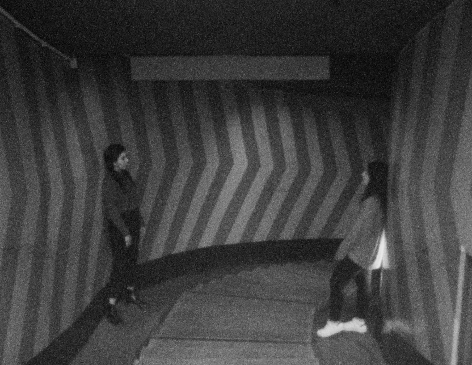 Zwei Jugendliche in einem Durchgang mit gestreiften Wänden, Schwarzweiß